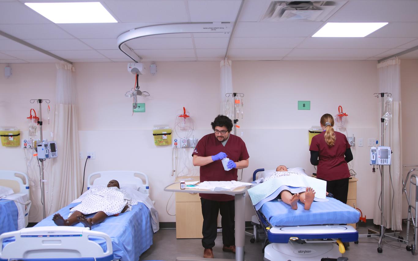 Students in scrubs in a hospital simulation lab